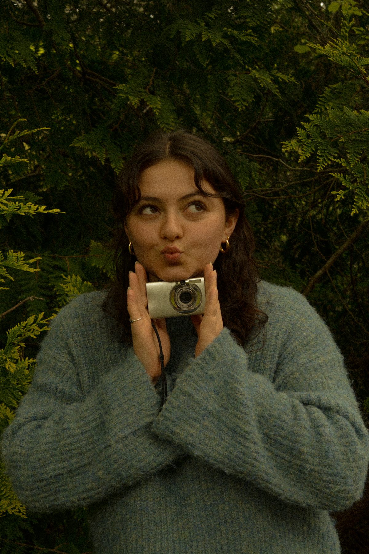 Anisa smiling with her camera among the trees